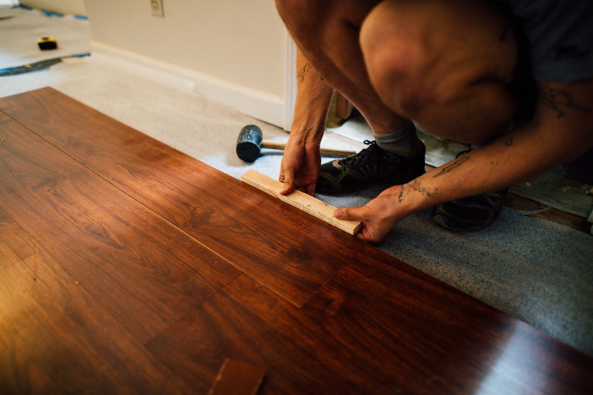 Installer fitting a new wood floor plank