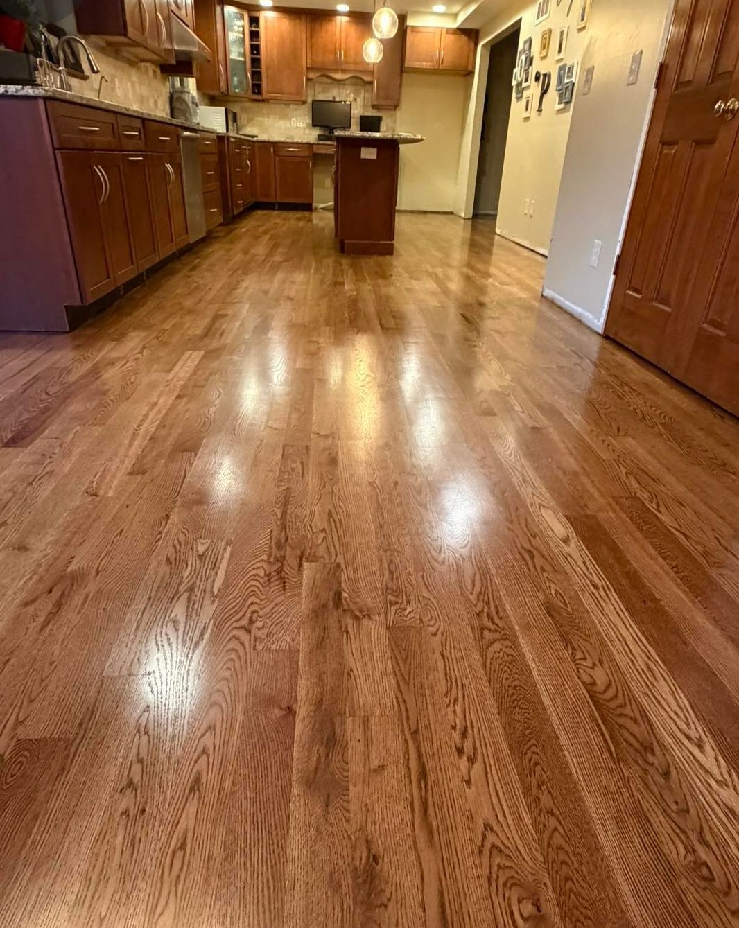 Rich, glossy hardwood floor in a living room with a stone fireplace