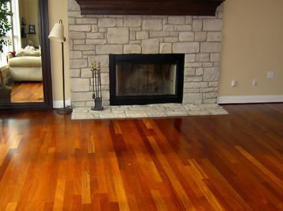 Rich, glossy hardwood floor in a living room with a stone fireplace